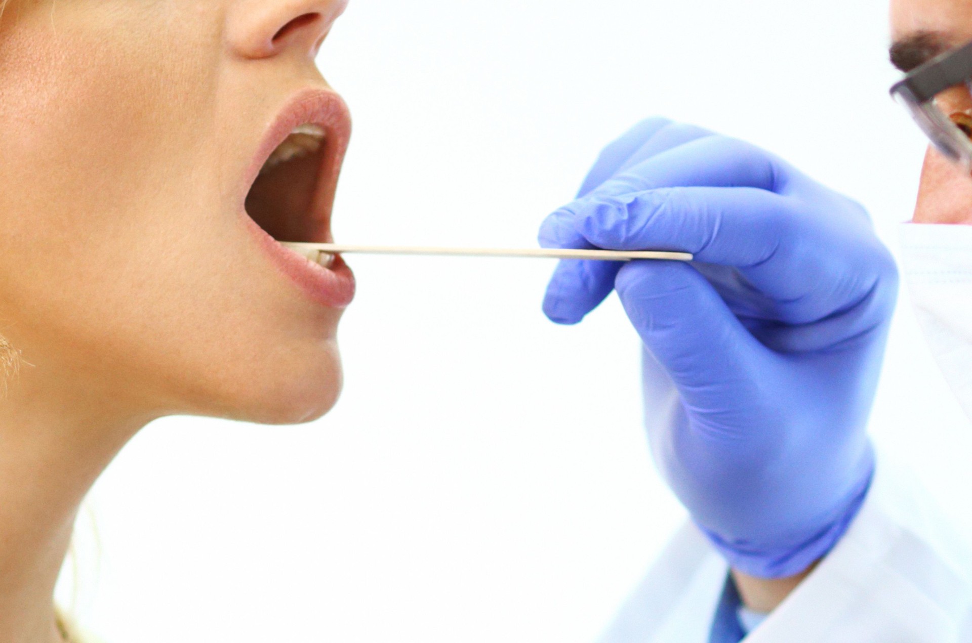 Dovtor examining patient's sore throat.